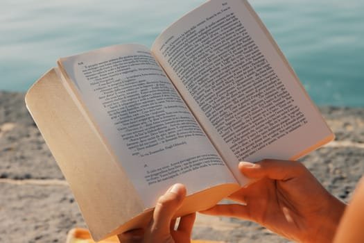 A person enjoys reading a book by the seaside in Syracuse, Sicily.